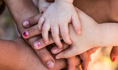 Several adults and children put their hands together