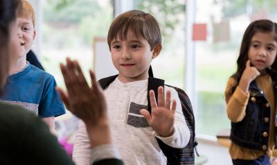 teacher and 3 children greeting each other outside