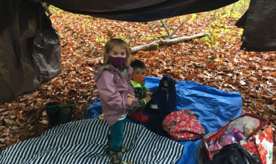 children playing in the woods in a crafted tent