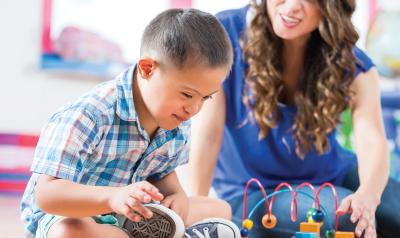 A teacher observes as a child plays with toys.