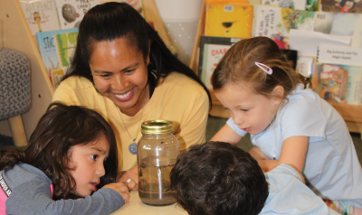 Feature Teacher Cecilia Fowler with students looking in a jar