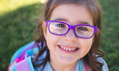 Young girl outside with backpack on.