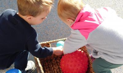 Two children look through a basket of balls.