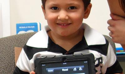 Child showing his artwork on a tablet.