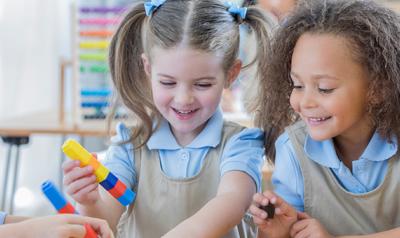 Three students playing with toys in a classroom