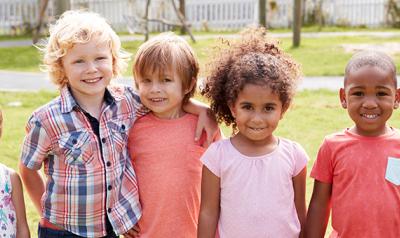 Group of young children holding hands outside.