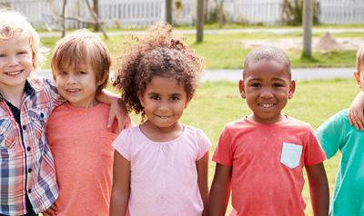 A diverse group of preschool-aged children posing together outside