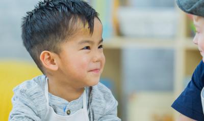 Two preschoolers smiling at each another