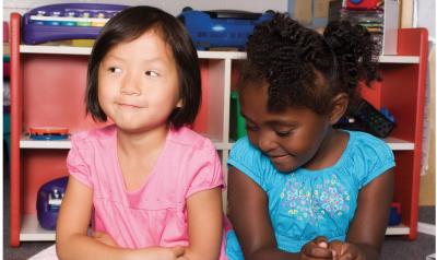 Two girls sitting close to each other, but not talking.