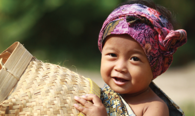 Young child in Indonesia with basket and colorful headscarf