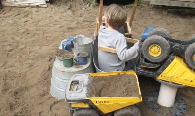 Child in poop machine in outdoor sandbox