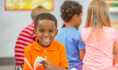 A young boy smiling and reading a book