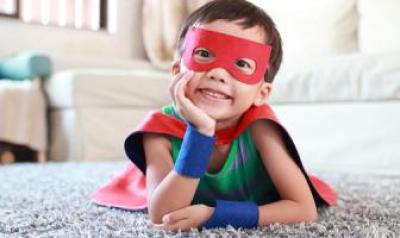 preschool boy dressed in a superhero cape and mask