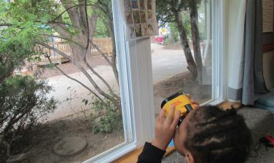 Child looking out window with binoculars