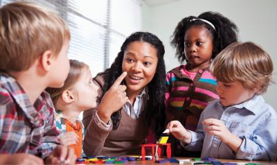 Teacher and preschool age students sitting at table with materials