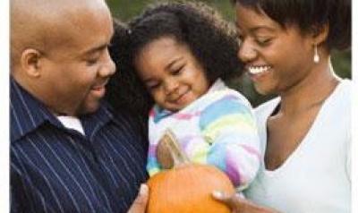 father, mother, and daughter holding a pumpkin