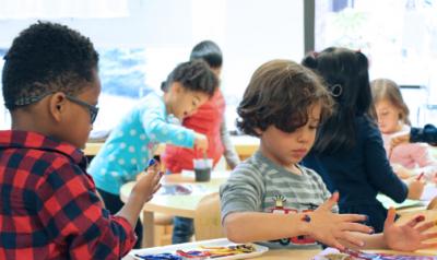 Two young boys in the classroom fingerpainting