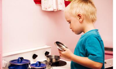 young boy playing with a kitchen playset in classroom