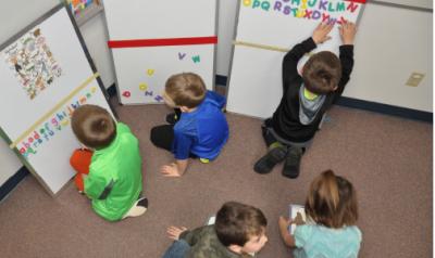 Five Kindergarten aged boys in a classroom playing with learning tools