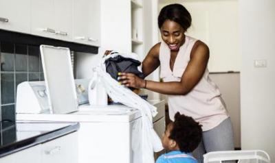 Mother talking with her child while doing laundry