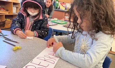 Children making signs in a classroom.