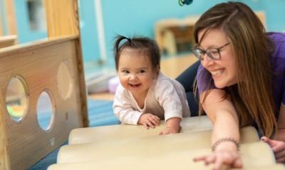 A teacher helping a toddler learn to crawl