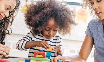 Two adults helping a child build blocks