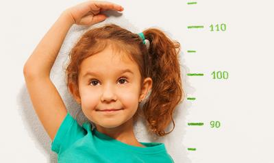 Little girl measuring herself with a blue shirt on 