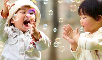Two toddlers playing outside with bubbles