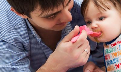 Father feeding his toddler daughter.