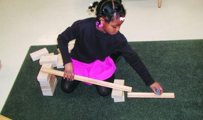 Young girl uses blocks to bulild