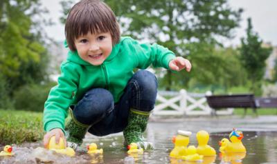 young boy plays with rubber ducks