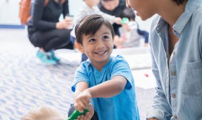 Child playing with recyclable materials with teacher