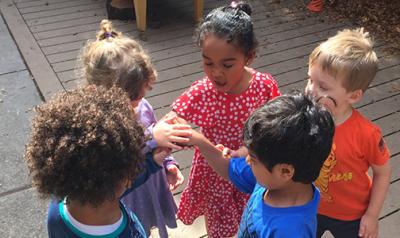 Five preschoolers standing outside holding hands