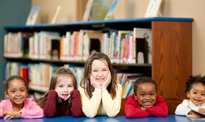 Five young children sitting at a table in the library