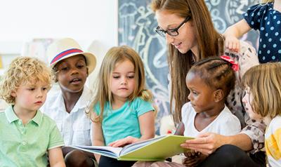 Teacher in a classroom reading to five children