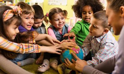 Diverse group of preschoolers with their hands on a globe