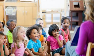 A teacher showing a picture book to children.