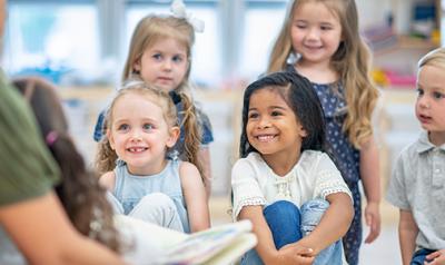 A group of young children listening to an adult talking.