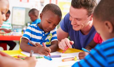 A teacher drawing with young children in a classroom.