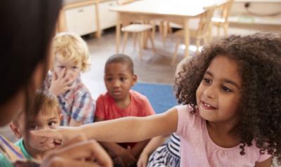 A child reaching towards a teacher.