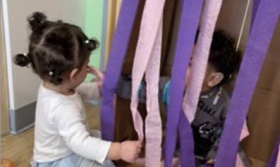 A toddler playing with streamers.