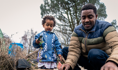 A father plays with his child outside.