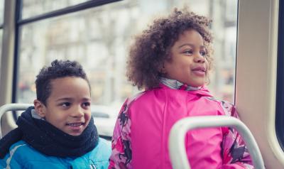 two kids sitting on a bus and looking out the window