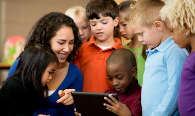 A group of children looking at an iPad with a teacher.