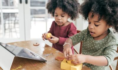 children playing with toys in front of an ipad