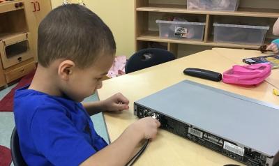 A child plugging in a projector screen.