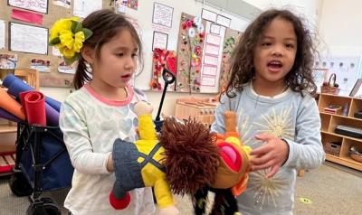 Two children playing with a puppet.