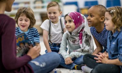 a teacher reading a book to a group of children