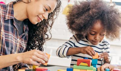 Two adults playing with blocks with a preschooler 